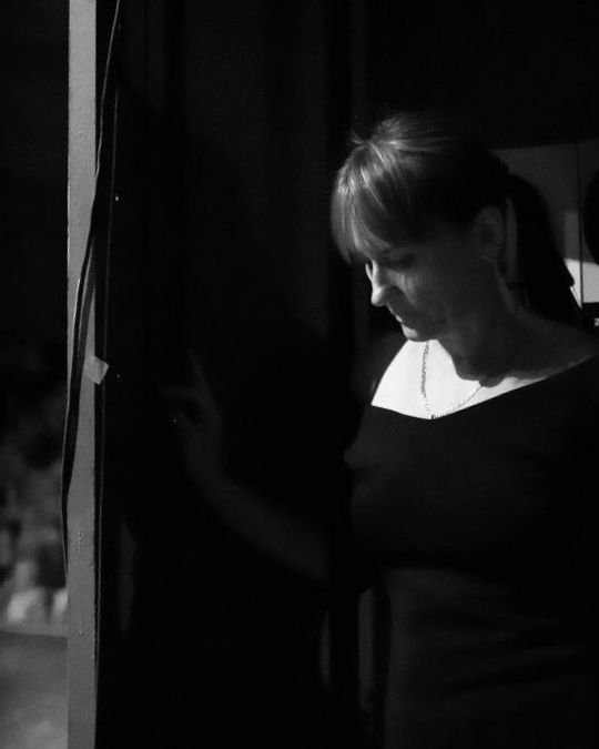 Black-and-white photo of Ivana waiting behind a stage curtain
