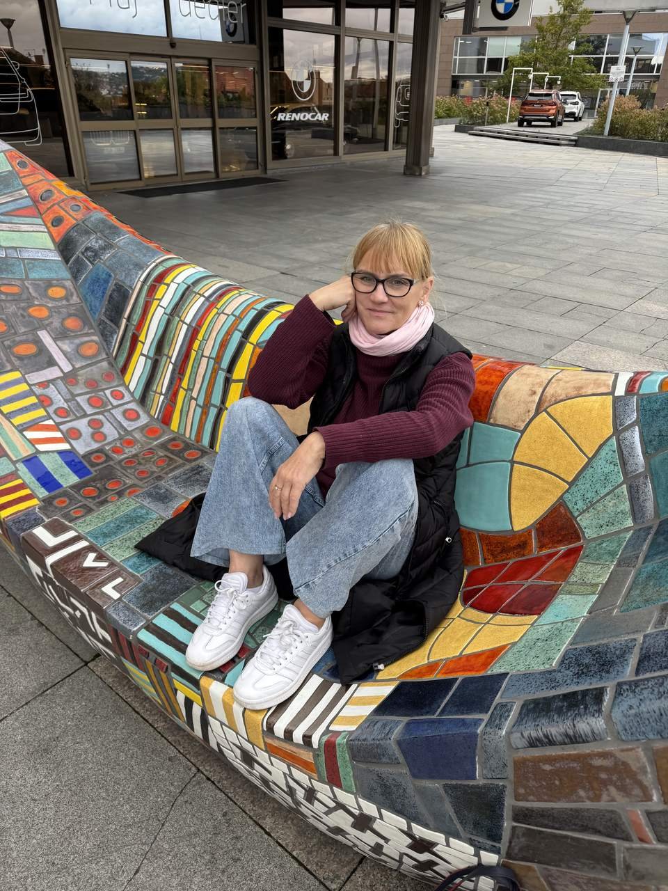 Ivana H. Kozmin sitting on a mosaic bench, smiling at the camera